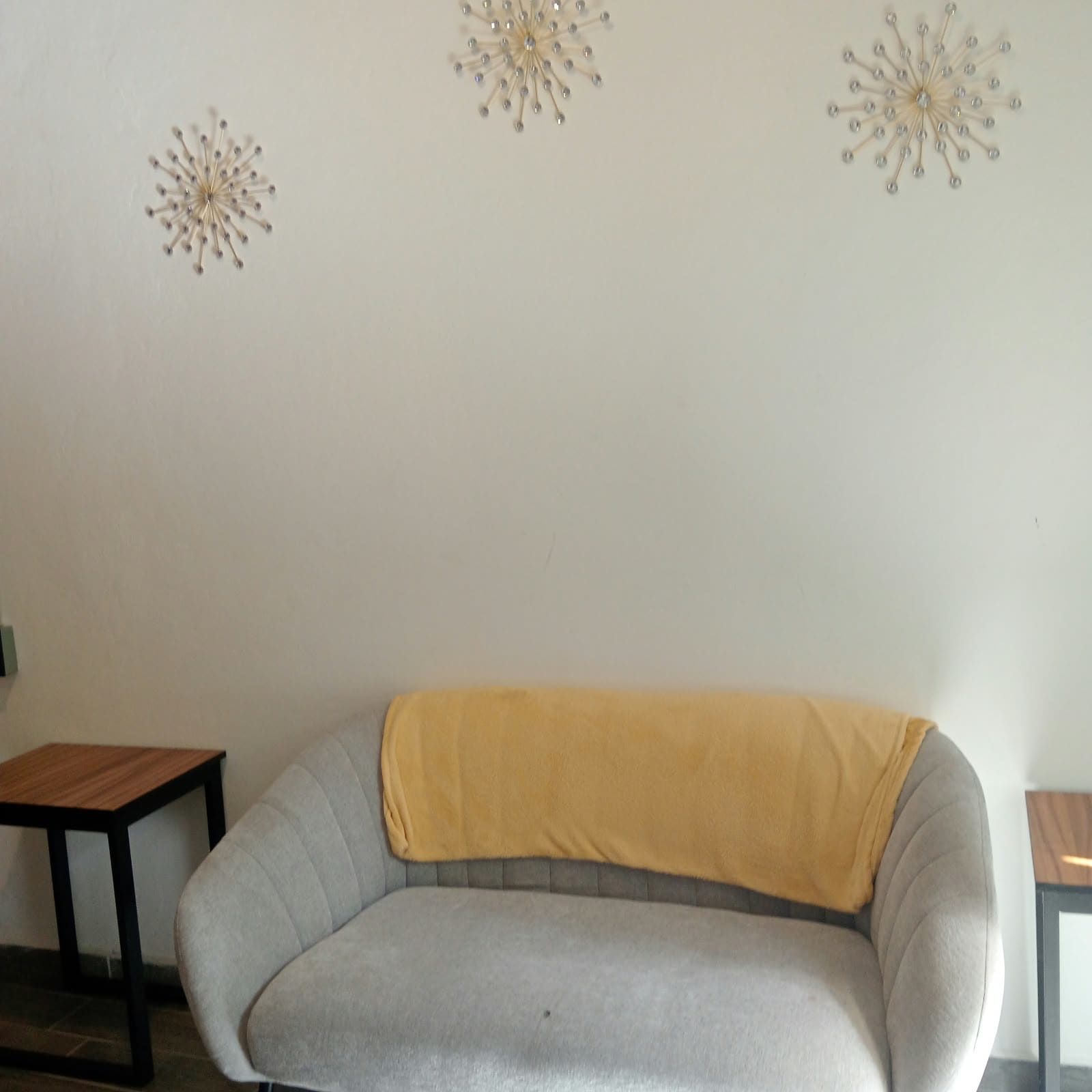 A room with a grey sofa, a small wooden table, and decorative wall art.