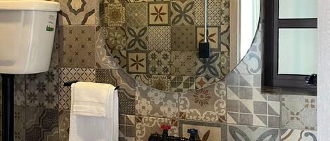A bathroom with a white sink, a mirror, and patterned tiles on the walls.