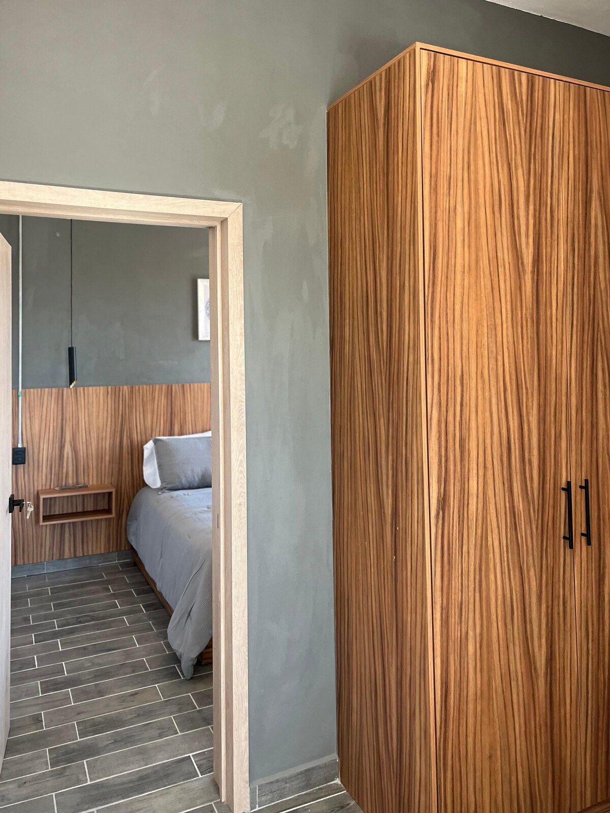 A bedroom with a bed, a wardrobe, and a small bedside table.