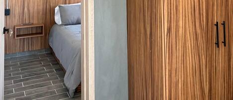 A bedroom with a bed, a wardrobe, and a small bedside table.