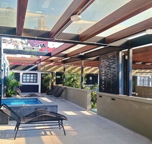 Una terraza en la azotea con piscina, sillones de descanso y vistas de la ciudad.