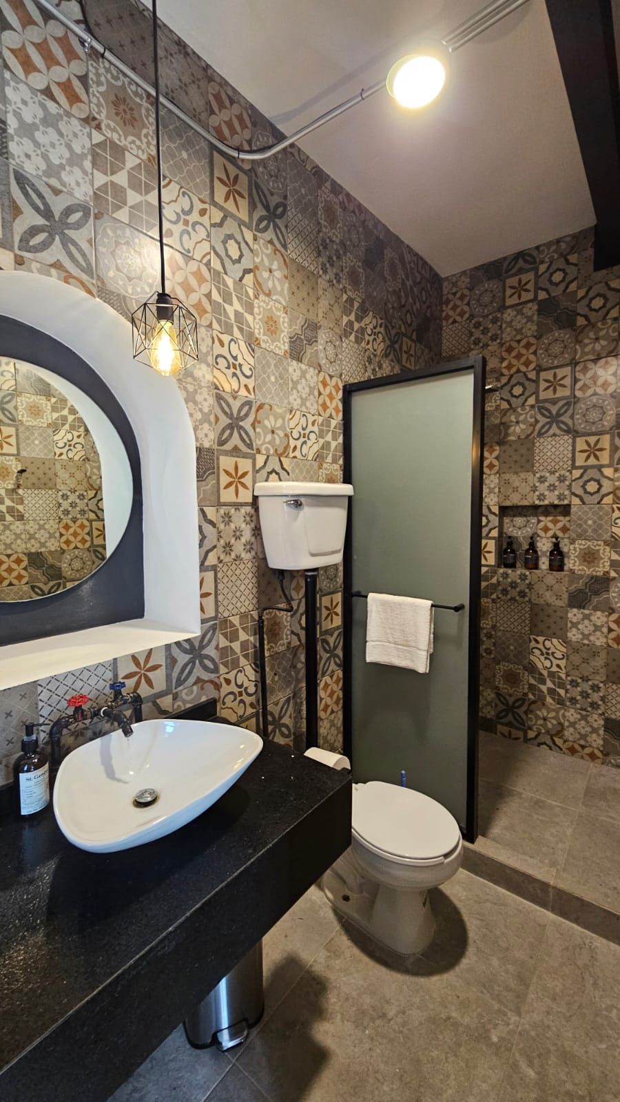 Une salle de bain avec un lavabo blanc, un miroir, des toilettes et des carreaux décoratifs sur les murs.