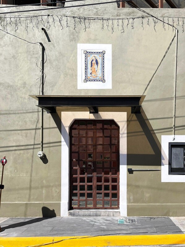 A building facade with a large wooden door, a small window, and a framed picture above the door.