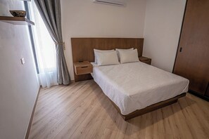 A bedroom with a wooden bed, white bedding, a nightstand, and a bedside table. - Laurelian 6 · Vare · Private suite near downtown (Oaxaca de Juárez)