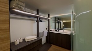 Ein modernes Badezimmer mit einem großen Spiegel, einem Waschbecken und einem Handtuchhalter.