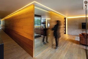 A modern interior with a wooden partition, a sofa, a television, and a person walking. - Sixth floor facing Parque España, Condesa (Mexico City)