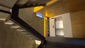 Ein modernes Interieur mit einer Treppe, einem Wandlifte und einer Tür.