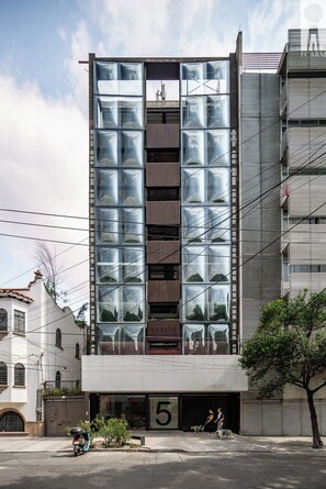 Ein modernes Gebäude mit Glasfassade, Hausnummer '5' und einem sichtbaren Eingang.