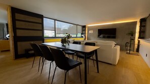 Ein moderner Wohnraum mit Essbereich, einer Couch und einem an der Wand befestigten Fernseher.