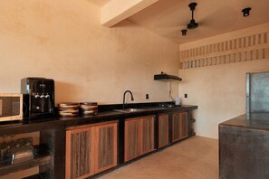 Eine Küche mit schwarzer Arbeitsplatte, Holzschränken, einer Spüle, einer Mikrowelle und einem Kühlschrank.