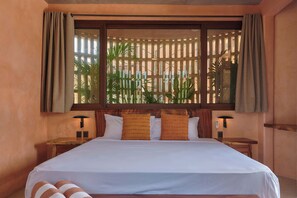A hotel room with a large bed, two bedside tables, a window with curtains, and a view of palm trees. - Casa Tintorera, steps from the shore (Puerto Escondido)