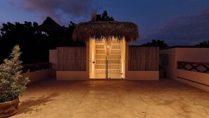 L’entrée d’un bâtiment avec un toit de chaume, une clôture en bois et un pot de fleurs.