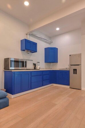 A modern kitchen with blue cabinets, a stainless steel refrigerator, and a microwave. - Suite in La Punta, a minute from the sand (Puerto Escondido)