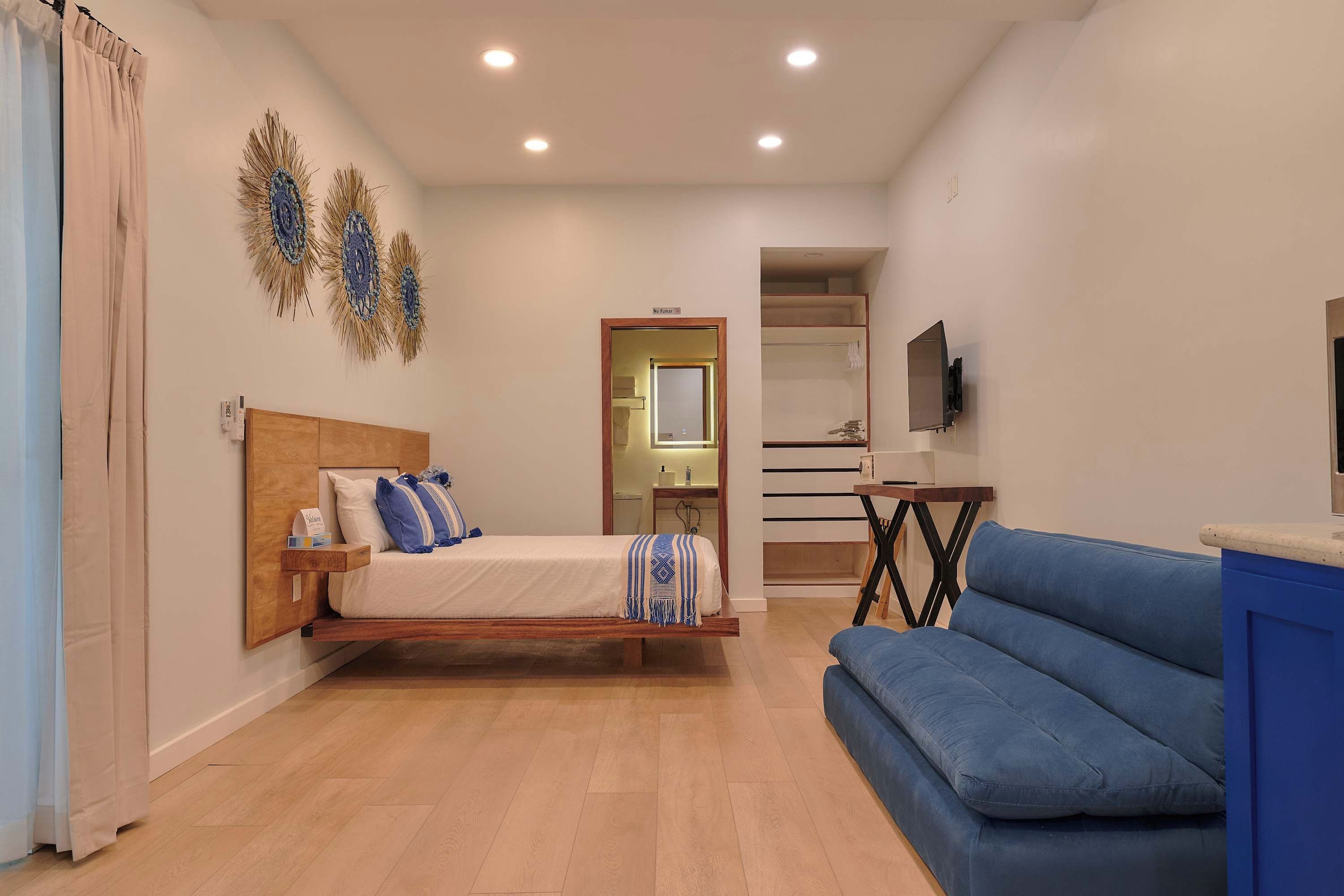 A bedroom with a bed, a blue sofa, a TV, and a small table.