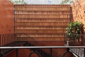Eine Treppe führt zu einem Balkon mit einem Metallgeländer, einem Holenzaun und einem Blumentopf.