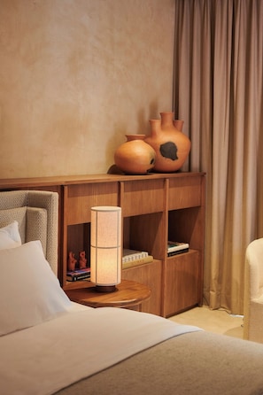 A hotel room with a bed, a nightstand, a lamp, and a shelf with decorative items. - Luxury Boutique Hotel in Downtown Oaxaca (Oaxaca de Juárez)
