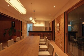 A conference room with a long table and chairs, a kitchen area, and a glass partition. - Luxury Boutique Hotel in Downtown Oaxaca (Oaxaca de Juárez)