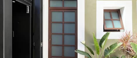 A building entrance with a glass door, a small window, and a black mat.