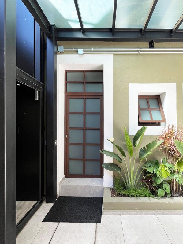 A building entrance with a glass door, a small window, and a black mat.