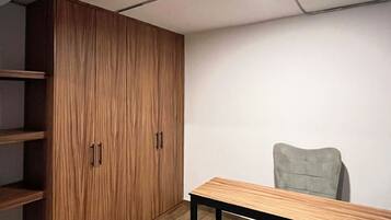 Quarto com guarda-roupa de madeira, uma mesa e uma cadeira.