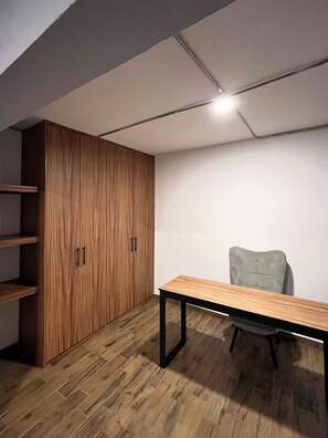 A room with a wooden wardrobe, a table, and a chair.