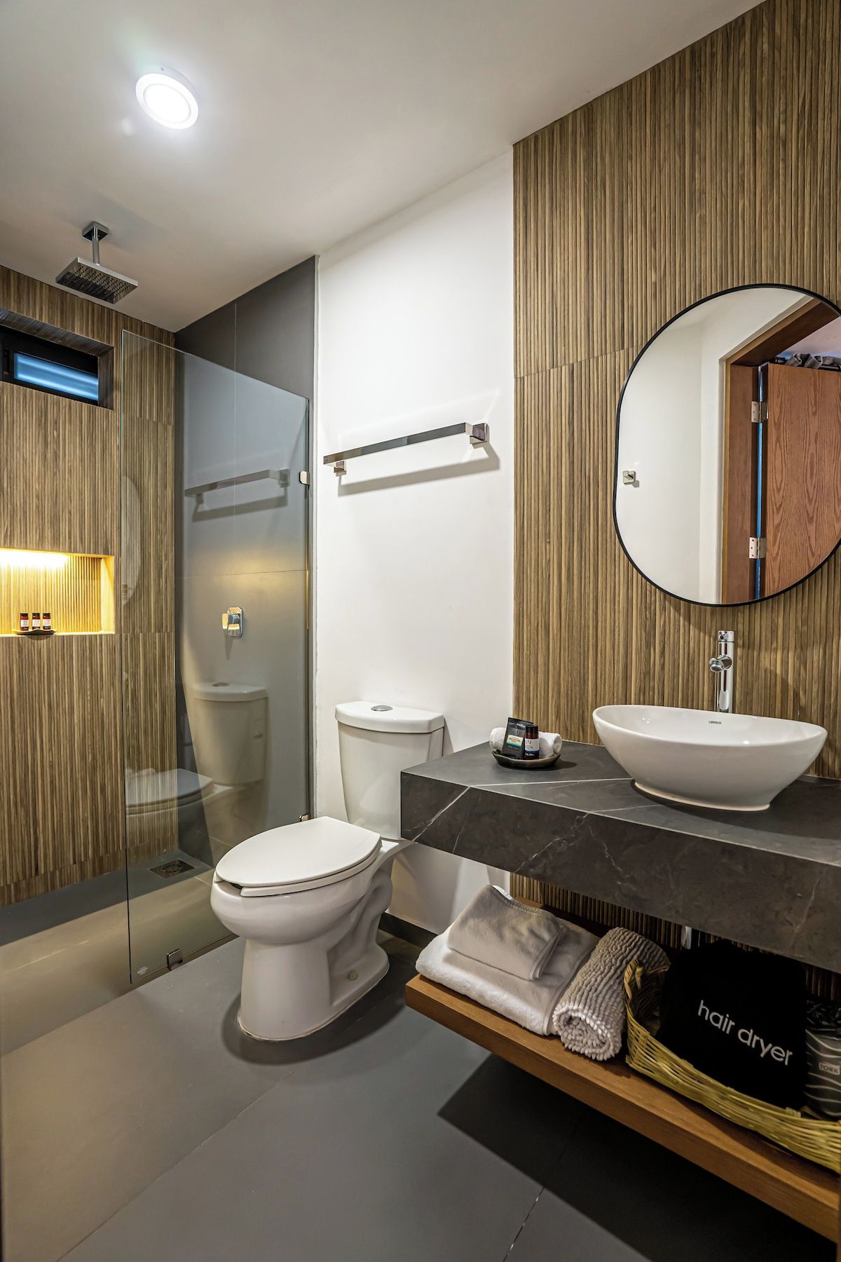 Ein modernes Badezimmer mit Toilette, einem Aufsatzwaschbecken und einem Spiegel darüber.