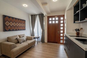 Ein Wohnzimmer mit einer Couch, einem kleinen runden Tisch und einer Tür zum Küchenbereich.