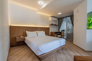 Ein Hotelzimmer mit einem hölzernen Bett, einem Nachttisch, einem Schreibtisch und einem Stuhl.