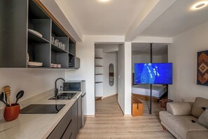 Una cucina moderna con piano cottura integrato, TV a schermo piatto montata a parete e zona pranzo con tavolo e sedie in legno.