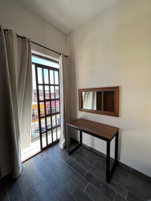 A room with a window, a table, and a mirror.