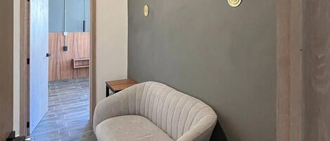A modern room with a curved sofa, a small wooden table, and a grey wall with decorative plates.