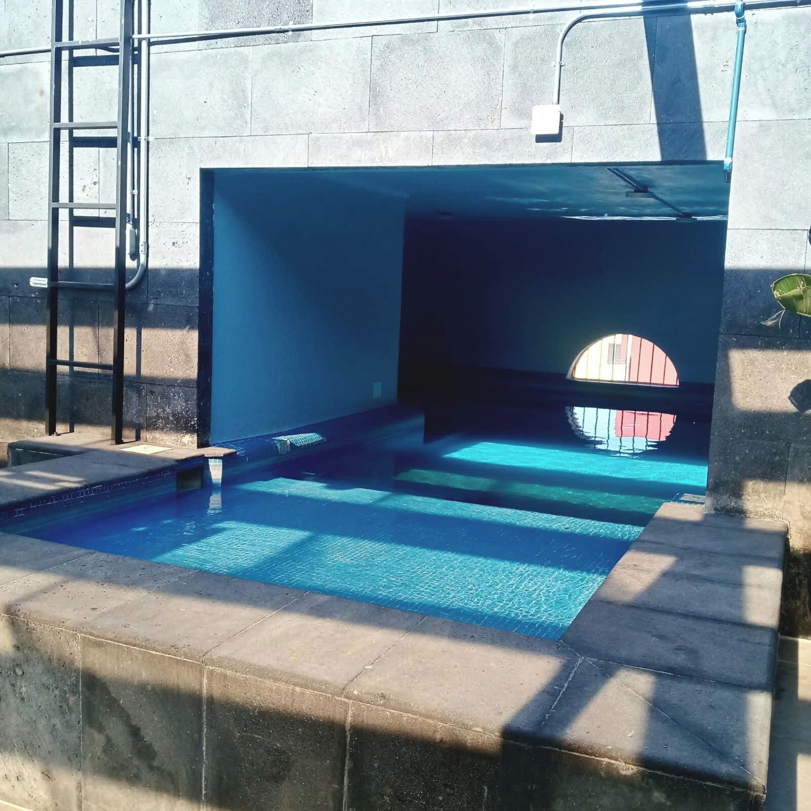 Ein Schwimmbecken mit einer Leiter und einem Rundfenster.