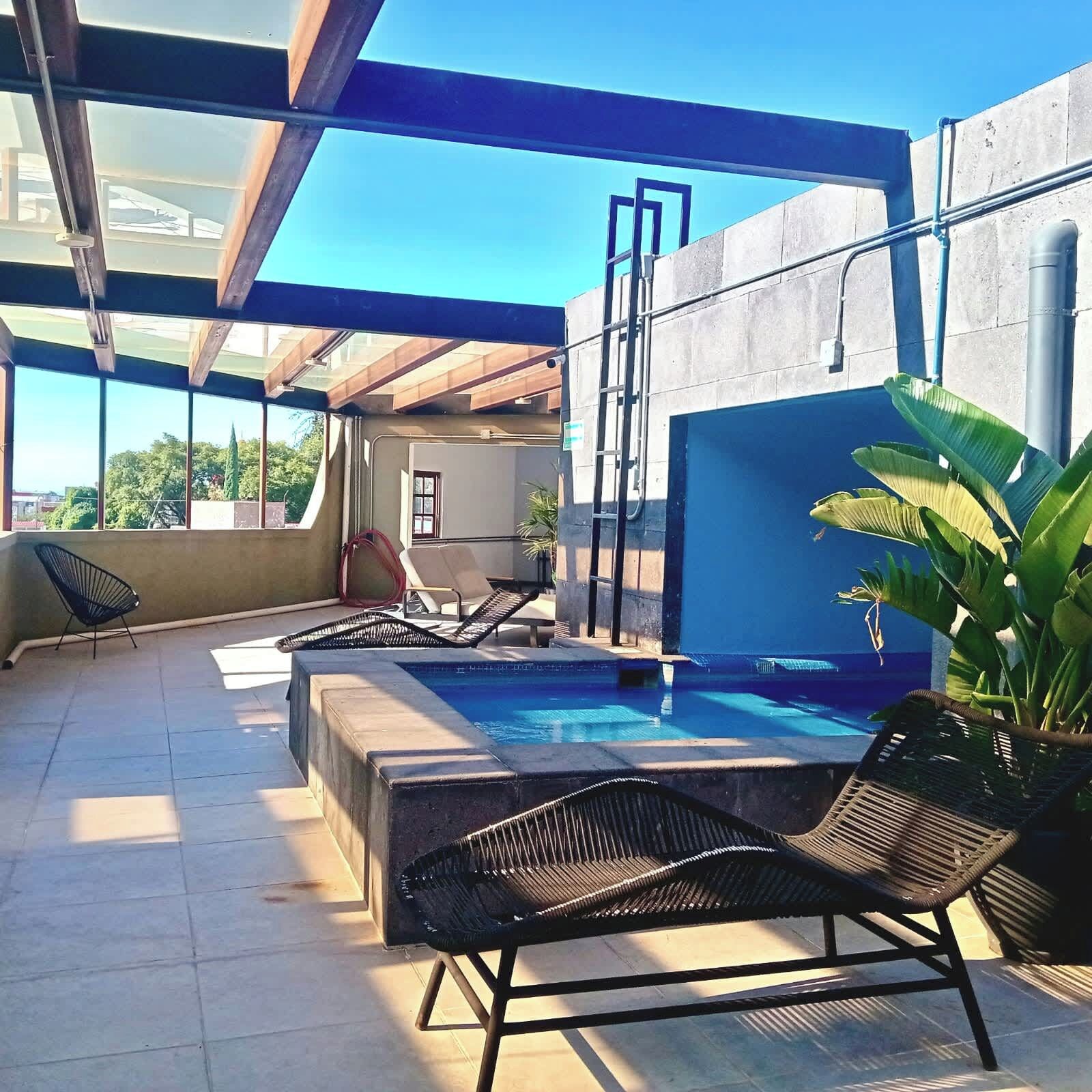 An outdoor swimming pool with lounge chairs and a view of the ocean.