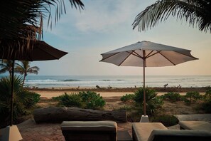 A beachside lounge area with outdoor seating and umbrellas, overlooking the ocean.