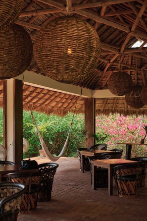 An outdoor seating area with wicker furniture and a thatched roof.