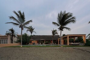 A resort with a pool, palm trees, and thatched-roof structures. - Casa Juliana · Private suite · Beachfront property (Puerto Escondido)
