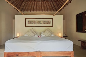 A bed with a wooden frame, two pillows, a white bedspread, and two wall-mounted picture frames. - Full Beachfront Estate · Jungle & Pacific (Puerto Escondido)