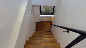Un escalier en bois avec une rampe noire menant à un palier doté d’une fenêtre.