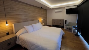 A hotel room with a bed, bedside tables, a wardrobe, a chair, a television, and an air conditioning unit. - Eighth floor facing Parque España, Condesa (Ciudad de México)