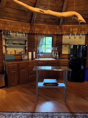 A kitchen with wooden cabinets, a stainless steel sink, and a black refrigerator.