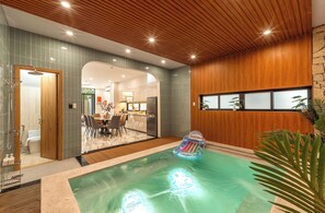 Un intérieur moderne avec une piscine, un plafond en bois et un coin repas.