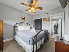 A bedroom with a bed, a ceiling fan, a dresser, and a door leading to a bathroom. - The Fairway Retreat | Golf Course Views | Pool & Spa | Dollywood (Pigeon Forge)