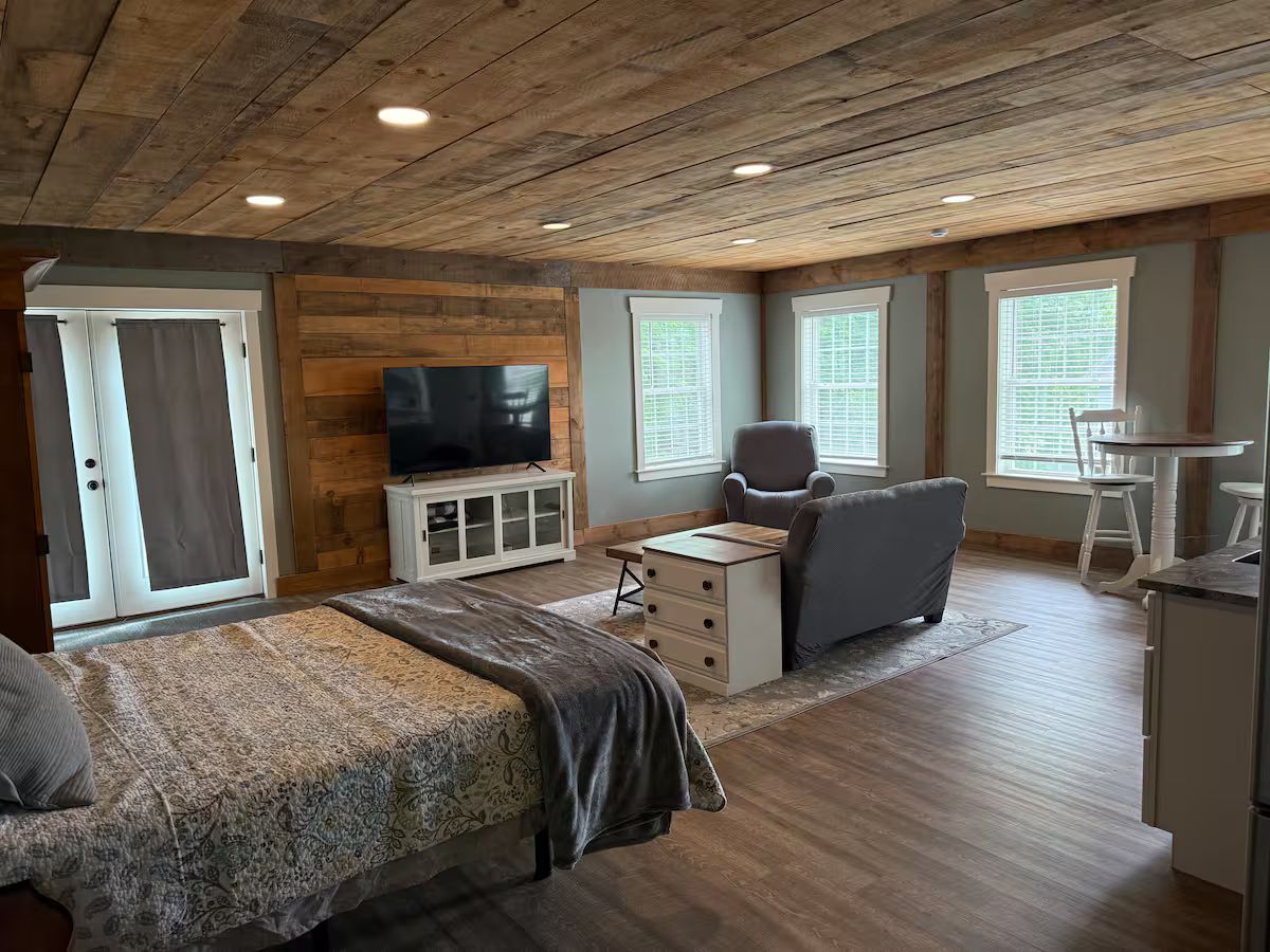 A bedroom with a bed, a TV, a desk, and a chair.