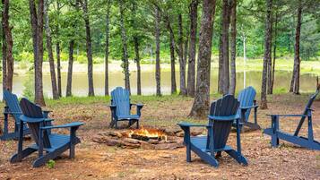 Un terrain de camping avec quatre chaises Adirondack disposées autour d’un feu de camp.