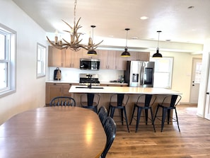 A modern kitchen with a central island, stainless steel appliances, and a chandelier with antler decorations.