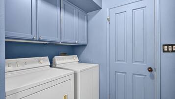 A laundry room with two white dryers and a blue door.