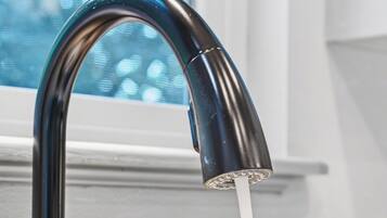 A kitchen sink with a modern faucet and a second faucet in the background.