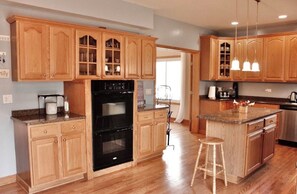 A kitchen with wooden cabinets, a black oven, and a granite countertop.