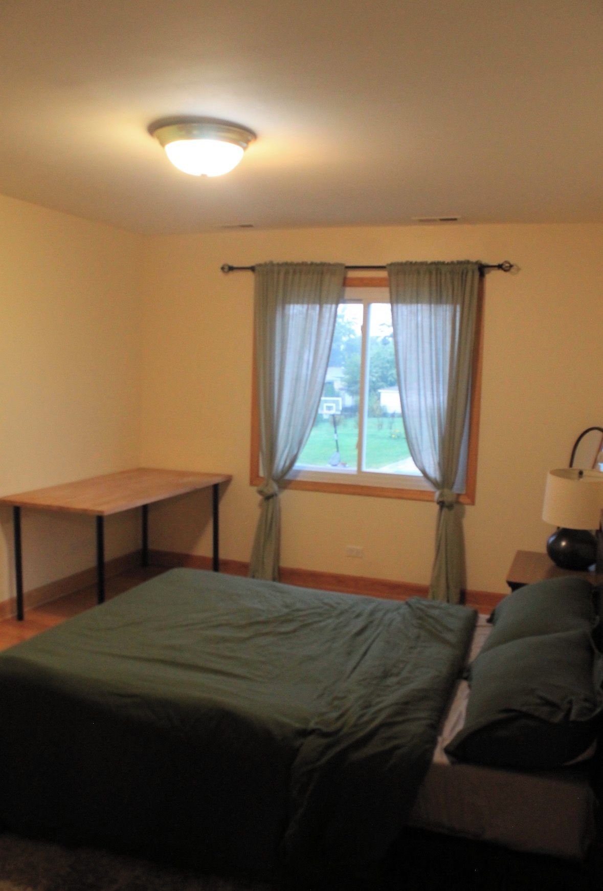 A room with a bed, a table, and a window with curtains.