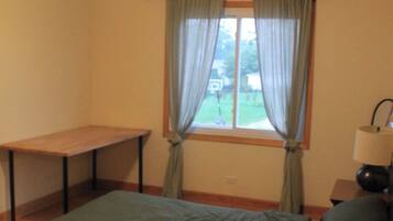 A room with a bed, a table, and a window with curtains.